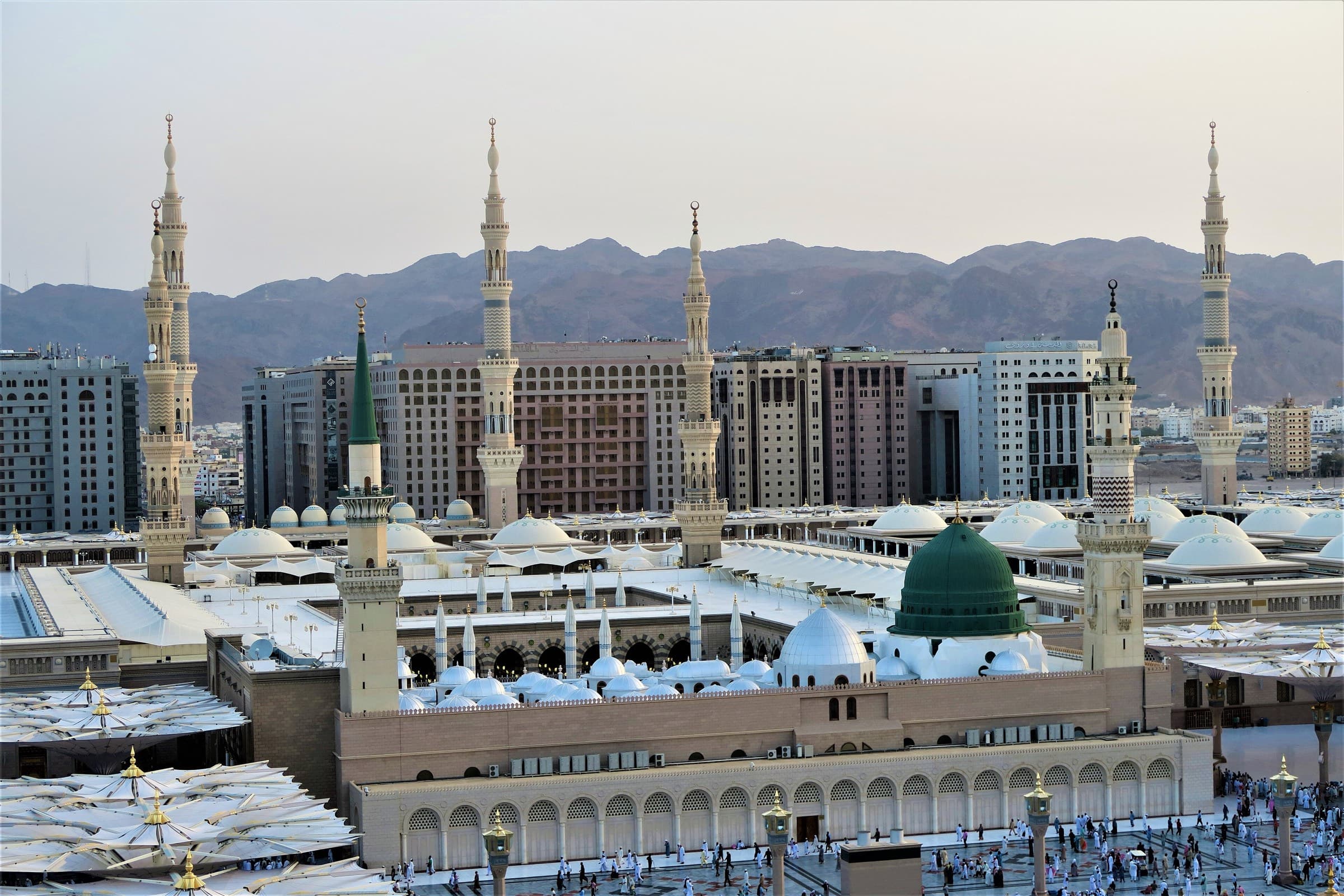 Al-Masjid an-Nabawi in Medina at dusk, its green dome and minarets above the courtyard